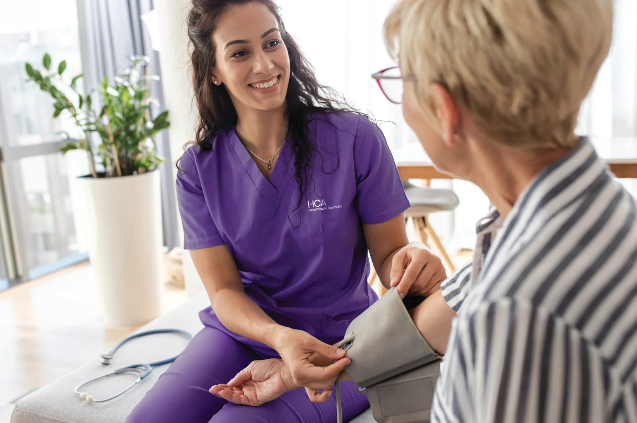 Nurse taking blood pressure of senior woman in home